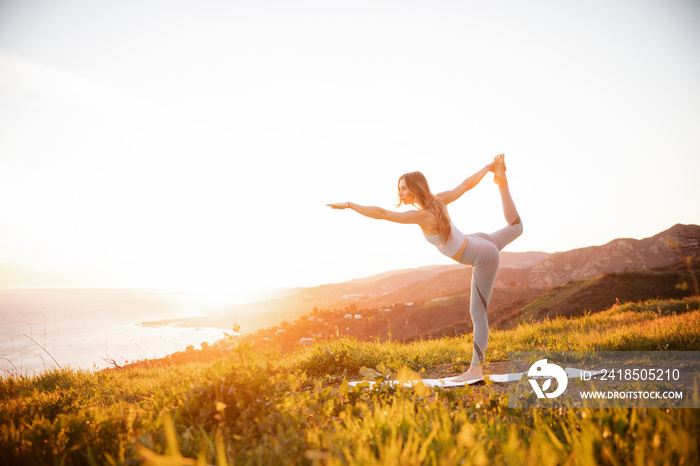 Full length of fit focused female athlete practicing balancing exercise on mountain against clear sk