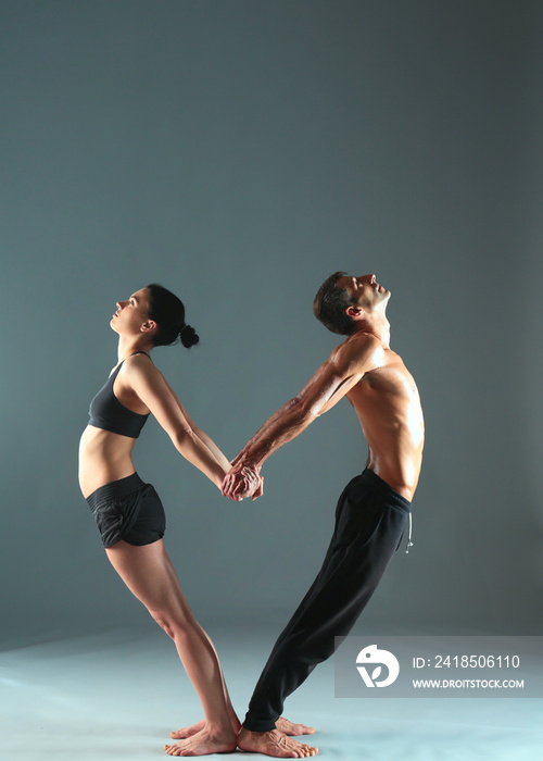 Young couple practicing acro yoga on mat in studio together