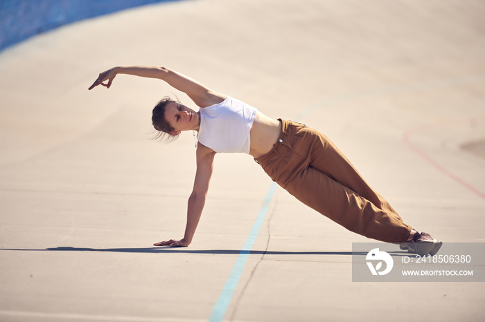 Beautiful young woman practices yoga in the city