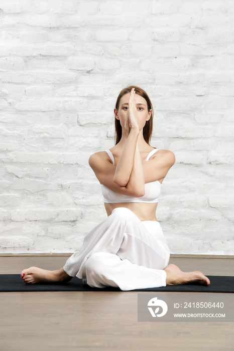 身穿白色套装的年轻女性练习伸展瑜伽姿势、健康和自我护理概念