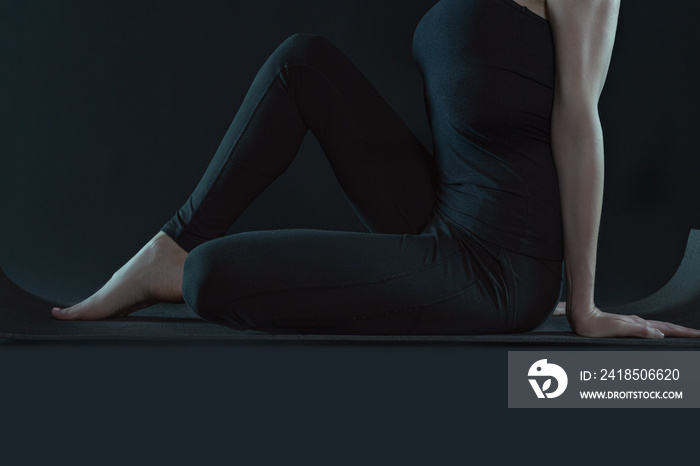 Young woman practicing yoga pose stratching . sport workout fitness. yoga mat and leggins on a dark 