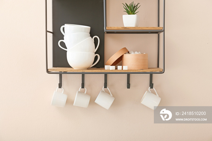 Shelf with cups on light wall