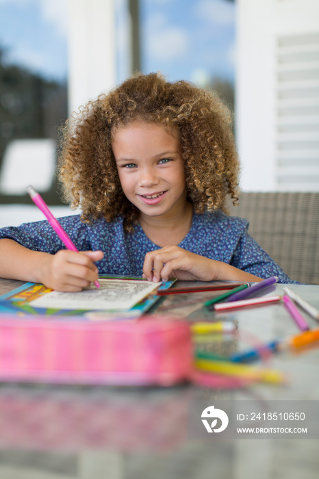 Portrait smiling girl coloring at table