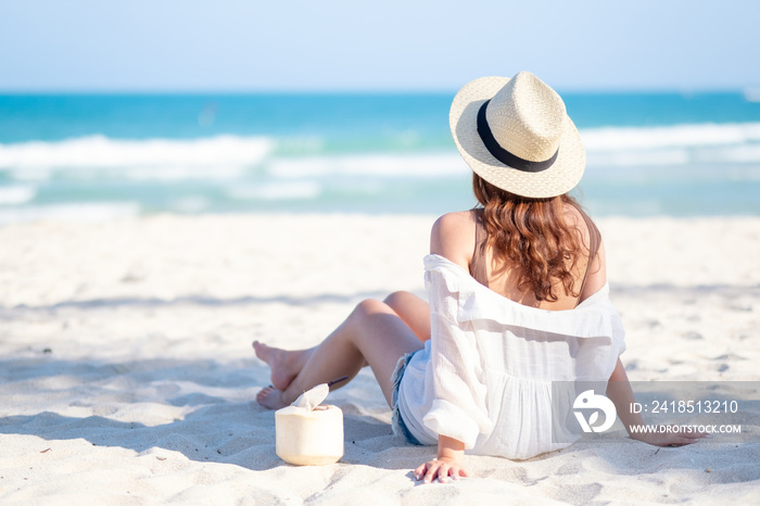 Portrait image of a beautiful asian woman enjoy sitting and drinking coconut juice on the beach