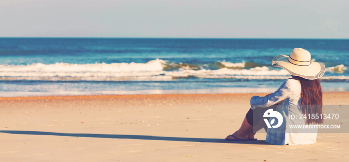 Woman in a hat sitting on the beach