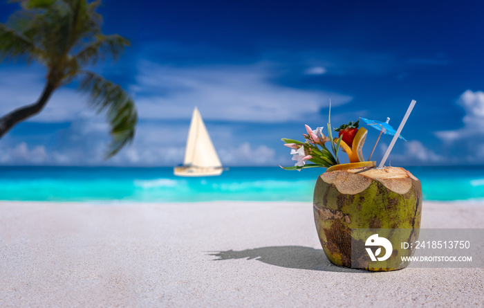 Coconut drink on a sandy beach with sailboat