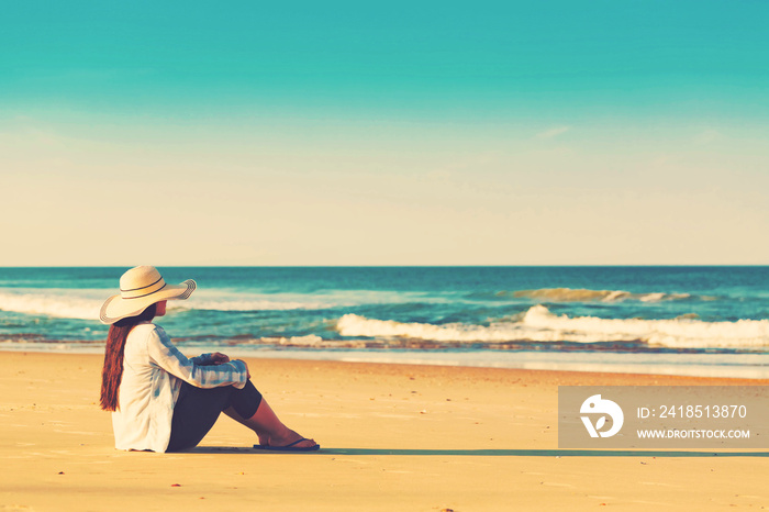 Woman in a hat sitting on the beach