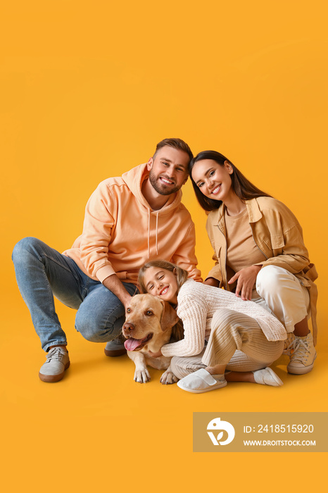 Happy parents with little daughter and cute Labrador dog on yellow background