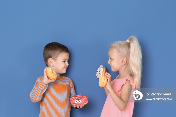 Little children with sweet donuts on color background