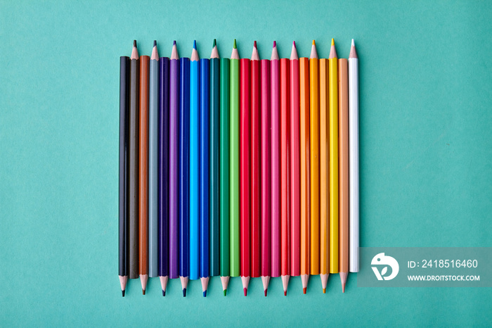 Row of multicolored pencils on color background. Set of colorful pencils on turquoise background. Co