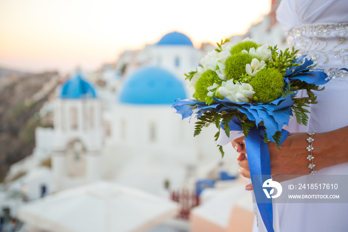 Bride holds wedding bouquet in white and green colors and blue decor against the backdrop of the sun