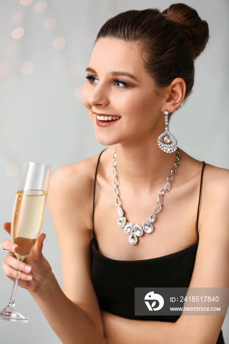 年轻女子，戴着漂亮的珠宝，背景是一杯香槟