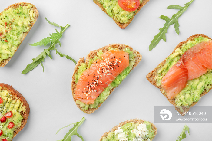 Different tasty avocado toasts on grey background