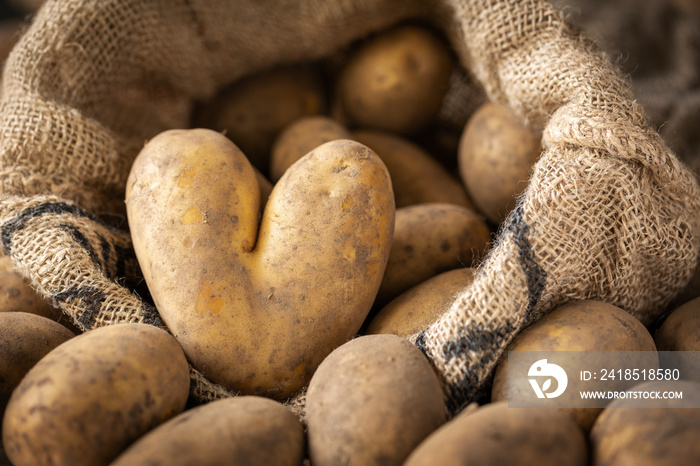 Heart-shaped potato and pile of raw potatoes