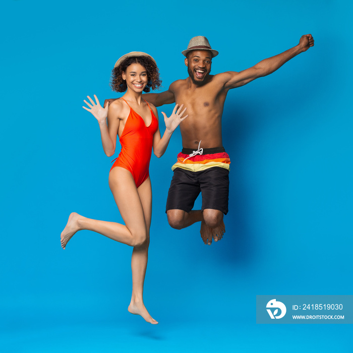 Playful energetic african american couple jumping on blue