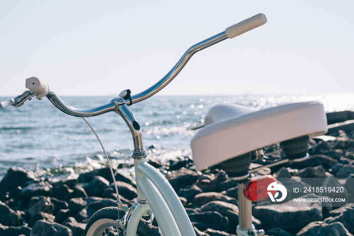 阳光明媚的日子里，蓝色大海背景下海滩上的女性复古自行车