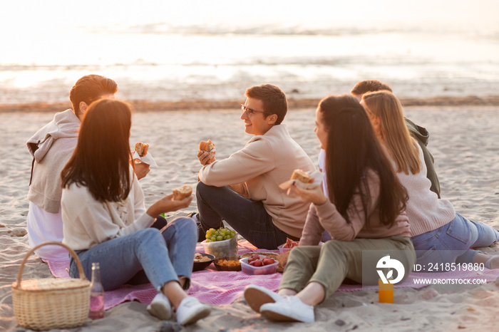 friendship, leisure and fast food concept - group of happy friends eating sandwiches or burgers at p