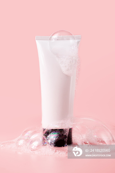 粉色背景上有肥皂泡的洗面奶管。美容护肤化妆品包装模拟