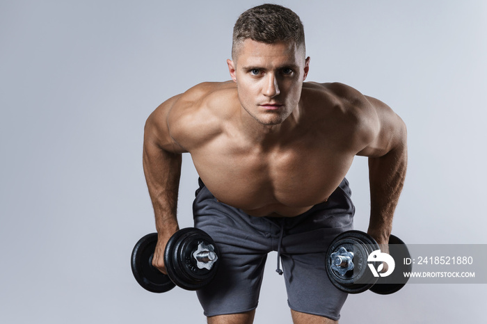 Young and muscular bodybuilder man working out with dumbbells