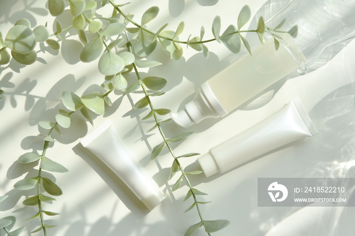 Cosmetic bottle containers packaging with green herbal leaves in shadow and light effect, Blank labe