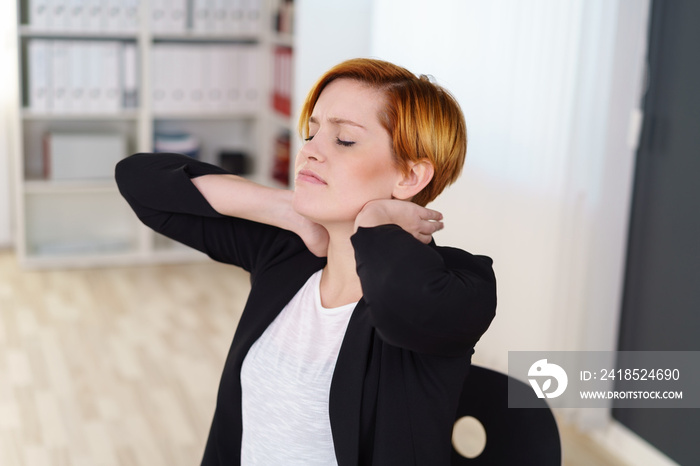 frau im büro dehnt ihren verspannten nacken