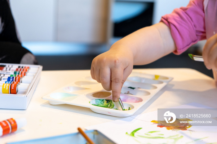 Child playing with watercolor tubes tempera oil paints