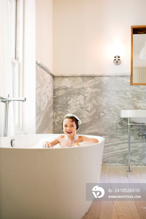 Portrait of boy (6-7) sitting in bathtub