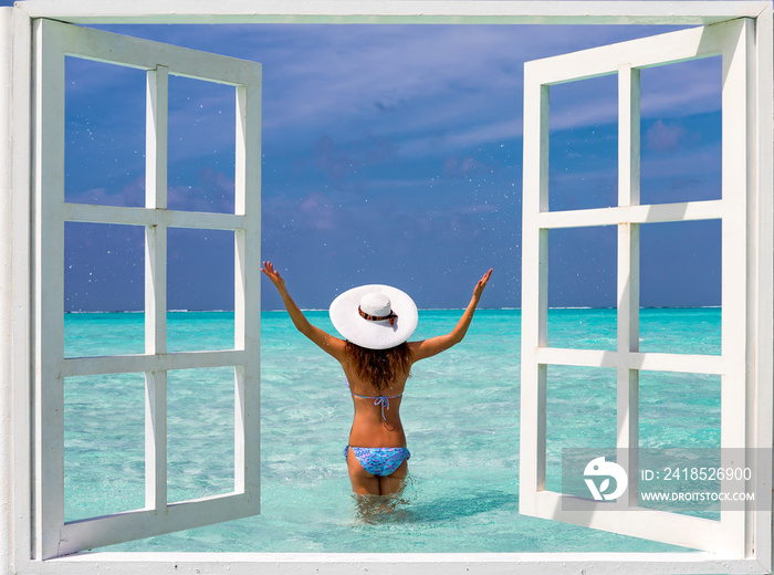 Frau mit Sonnenhut und Bikini vor offenem Fenster zu türkisem Meer unf blauen Himmel