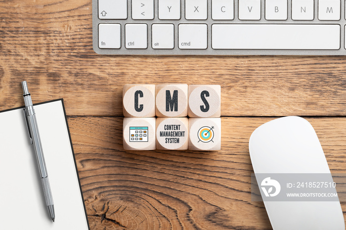 cubes with acronym CMS and a computer keyboard on wooden background