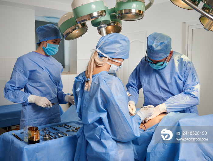 一群医生在手术室做整容手术。手术团队戴着防护面罩。