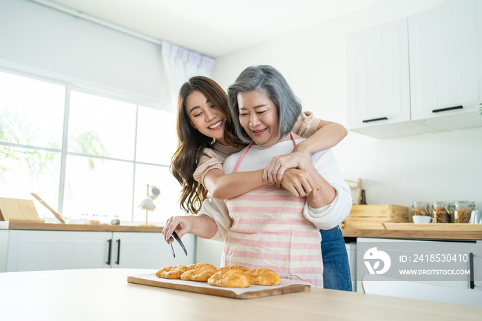 亚洲可爱的家庭，年幼的女儿看着年迈的母亲在厨房做饭