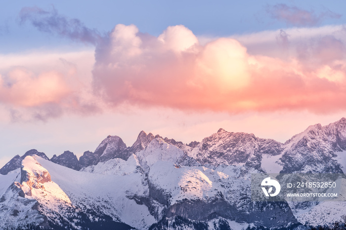 Sunset with dramatic sky and snowy mountain peaks illuminated by sunlight, Tatra Mountains in winter