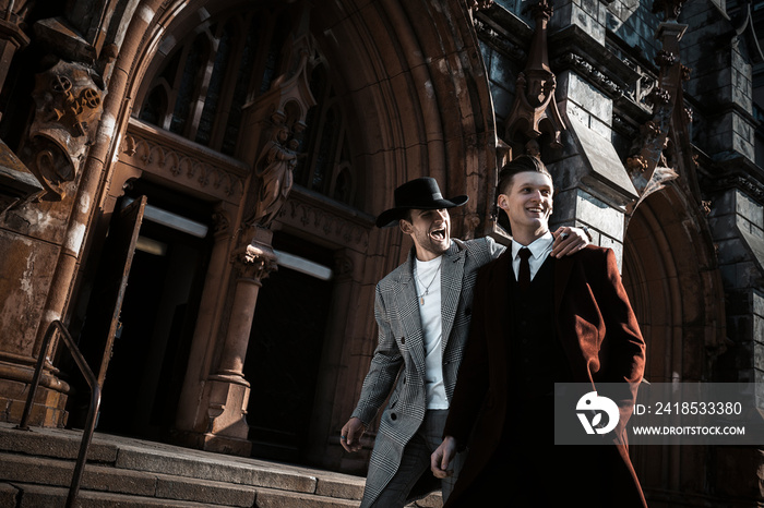 Two fashion beautiful man models posing on city street. Wearing in classic and casual closes. Suit, 