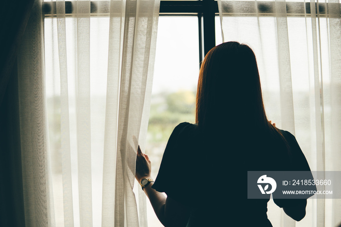 Thoughtful woman standing with looking at window, sad depressed teenager spending time alone at home