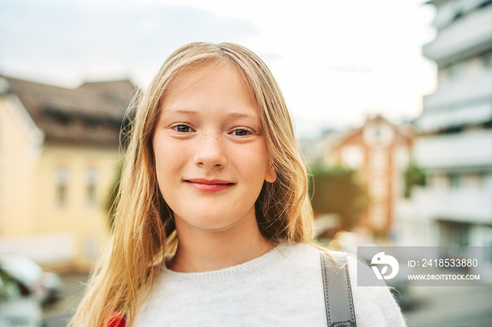 Outdoor close up portrait of adorable 10-12 year old girl wearing backpack