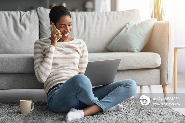 Joyful African American Woman Talking On Cellphone And Using Laptop At Home