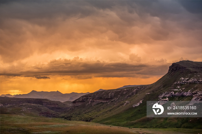 Cliffs and mountains under dramatic colorful storm clouds at sunset over the Drakensberg mountains s