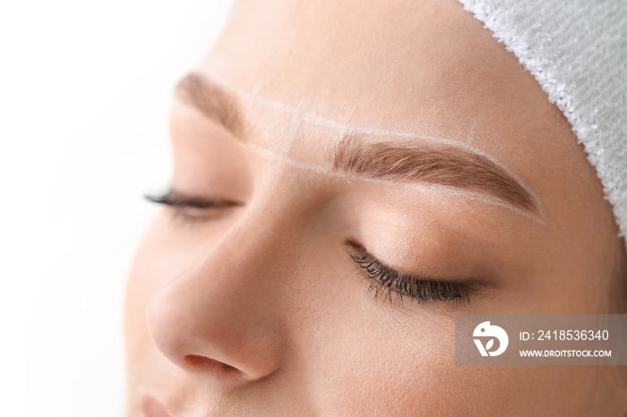 Young woman undergoing eyebrow correction procedure in beauty salon, closeup