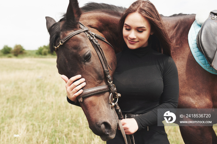 A happy girl communicates with her favorite horse. The girl loves animals andhorseback riding