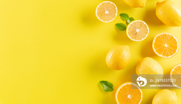 Summer composition made from oranges, lemon and green leaves on pastel yellow background. Fruit mini