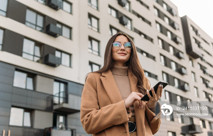 Business woman curly woman wearing trendy sunglasses walks down the central city street and uses her