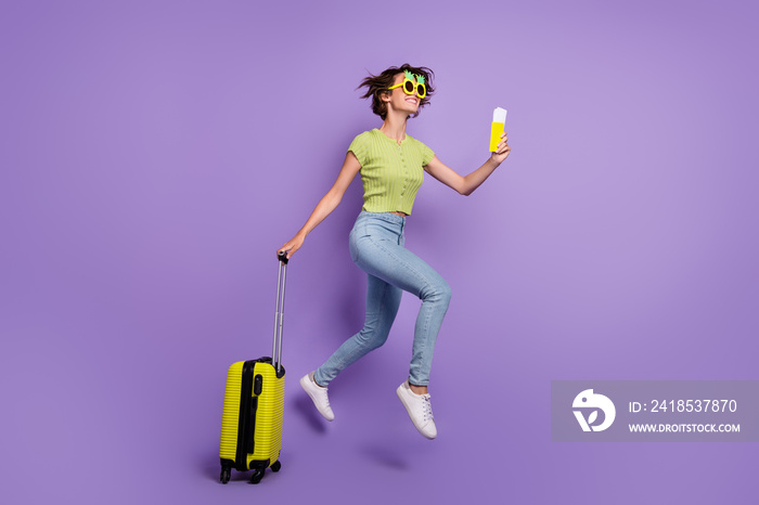 Photo of beautiful excited young lady wear green t-shirt smiling jumping holding passport baggage is