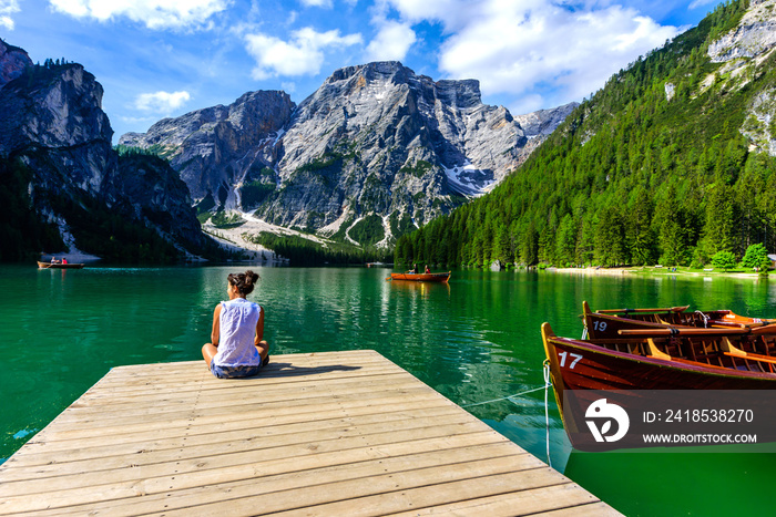 Woman relaxing on Pier at Lake Braies also known as Pragser Wildsee  in beautiful mountain scenery. 