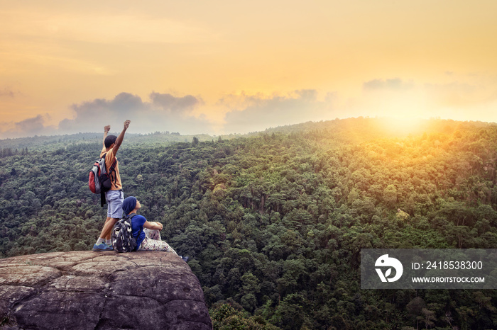 couples of traveling man and woman relax on top of  high mountain with beautiful sunset sky behind g