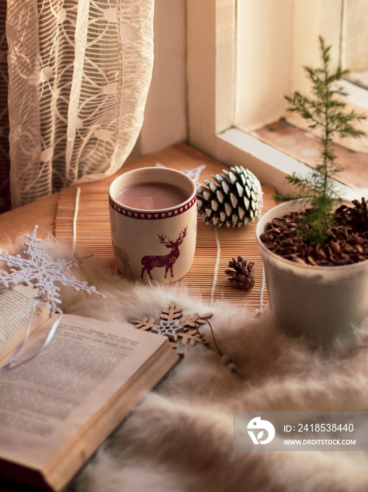 圣诞节静物。一杯可可，打开的书，冷杉锥，冷杉树，白毯子，手工雪花
