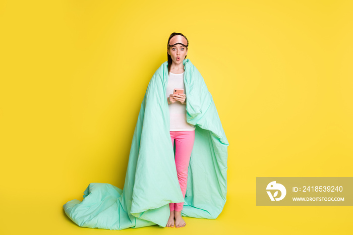 Full length photo of impressed girl wear sleepwear covered green blanket texting gadget isolated yel