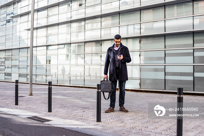 Middle aged man with a briefcase and a phone on the street