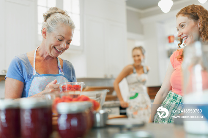 Mother and daughters making raspberry jam.