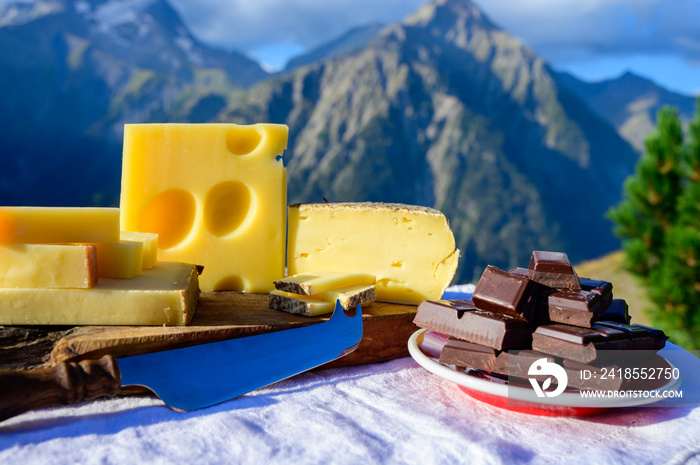 Tasty Swiss cheeses and dark pure chocolate, emmental, gruyere, appenzeller served outdoor with Alpi
