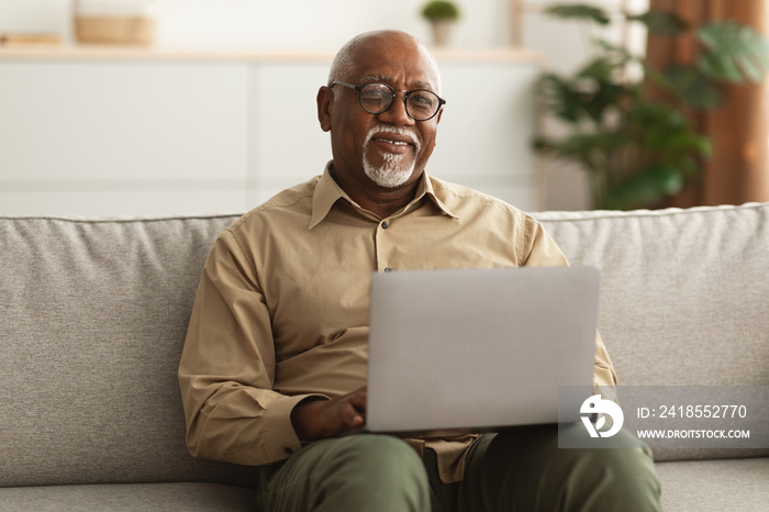 Mature Black Man Using Laptop Smiling To Camera At Home